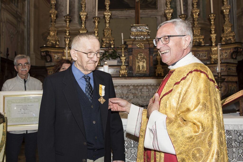 Mario Nervo riceve da don Gianni Pavese la medaglia d’oro al merito cristiano